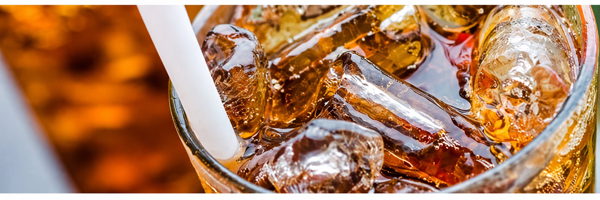 Verre de boisson brune glacée avec glaçons et paille blanche